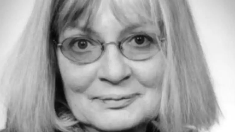 A woman with blonde shoulder length hair and circular glasses in a black and white photo. 