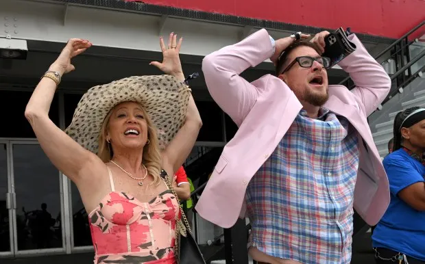 Anastasia Austen and Scott Davis of Louisville, celebrate after winning the trifecta in the second race at Pimlico Race Course. (Lloyd Fox/Staff)