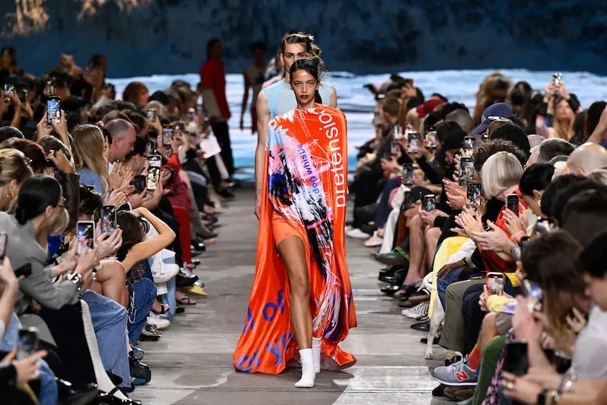 A model wears a red gown with scribbles of colour and words printed across it in all manner.