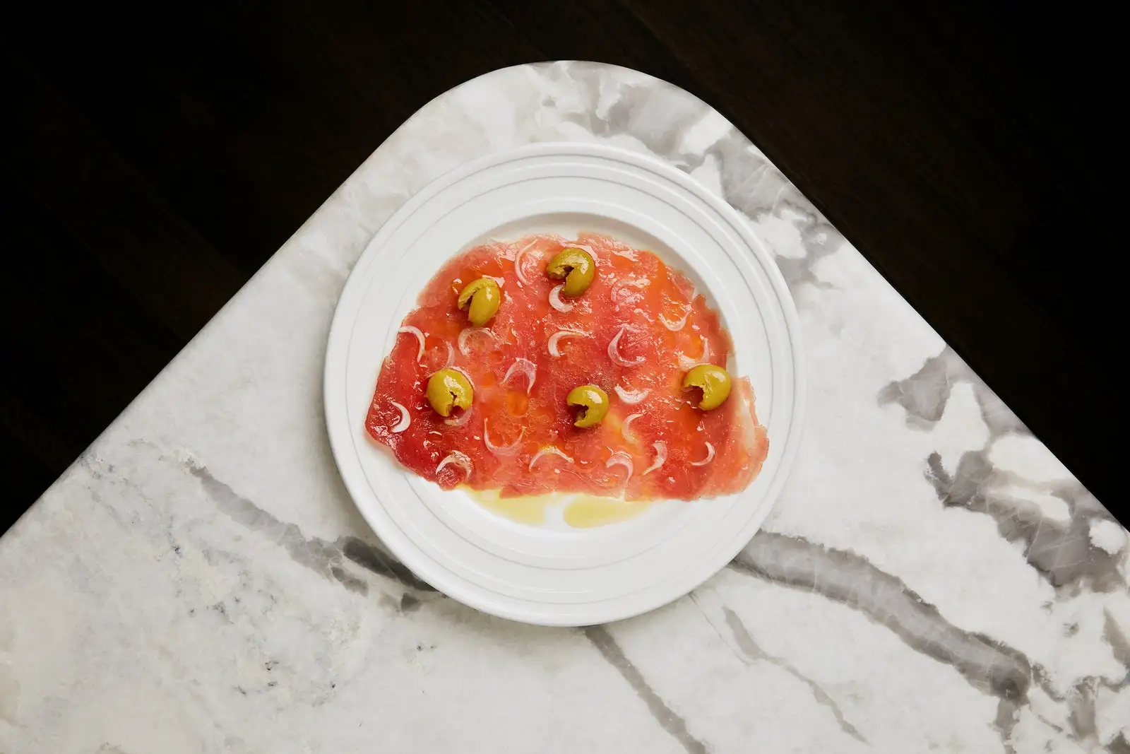 Tuna carpaccio with onions and green olives.