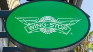 A close-up of a Wingstop (WING) sign on a green circle background.