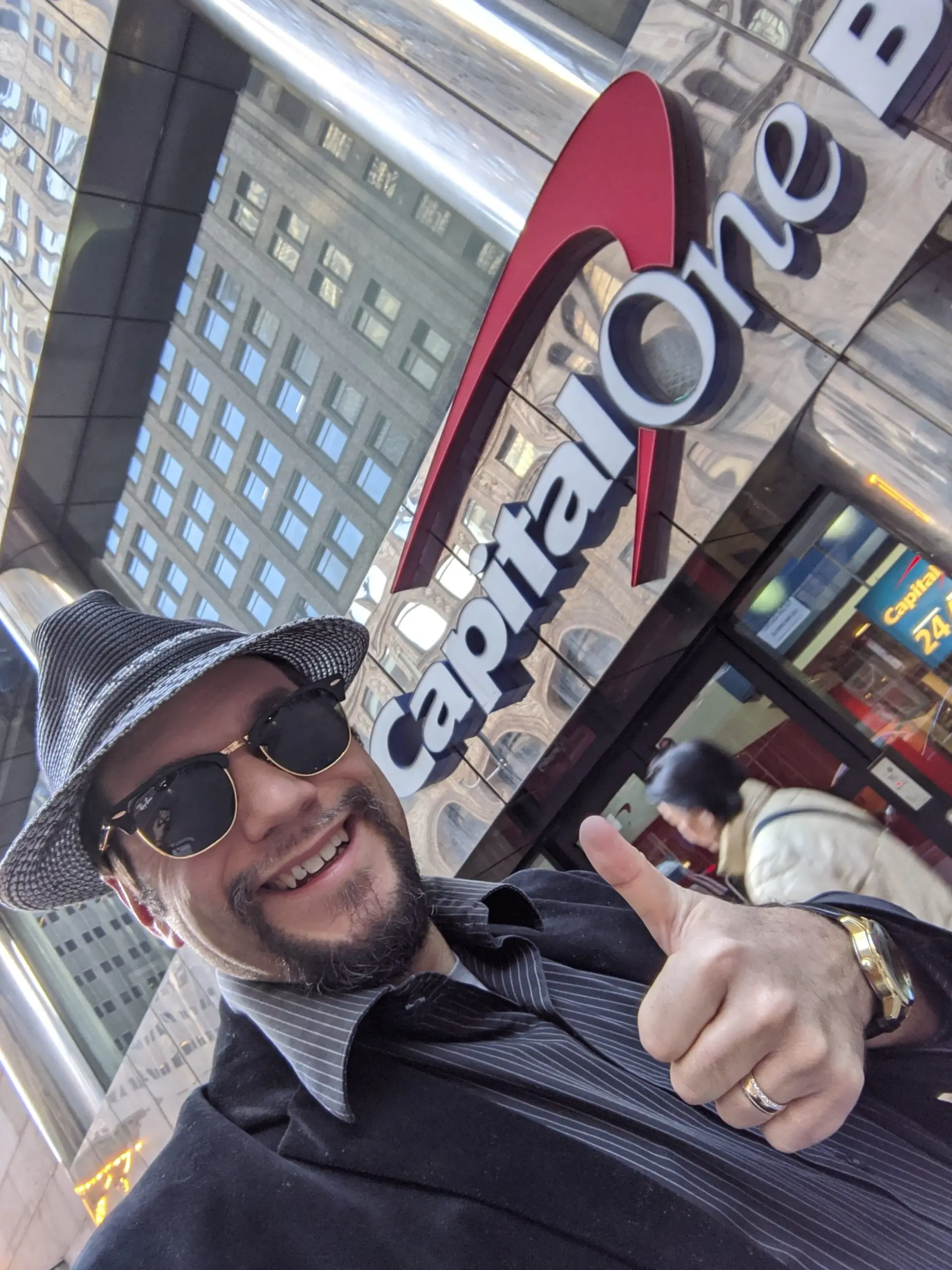 a man in a hat and sunglasses giving a thumbs up