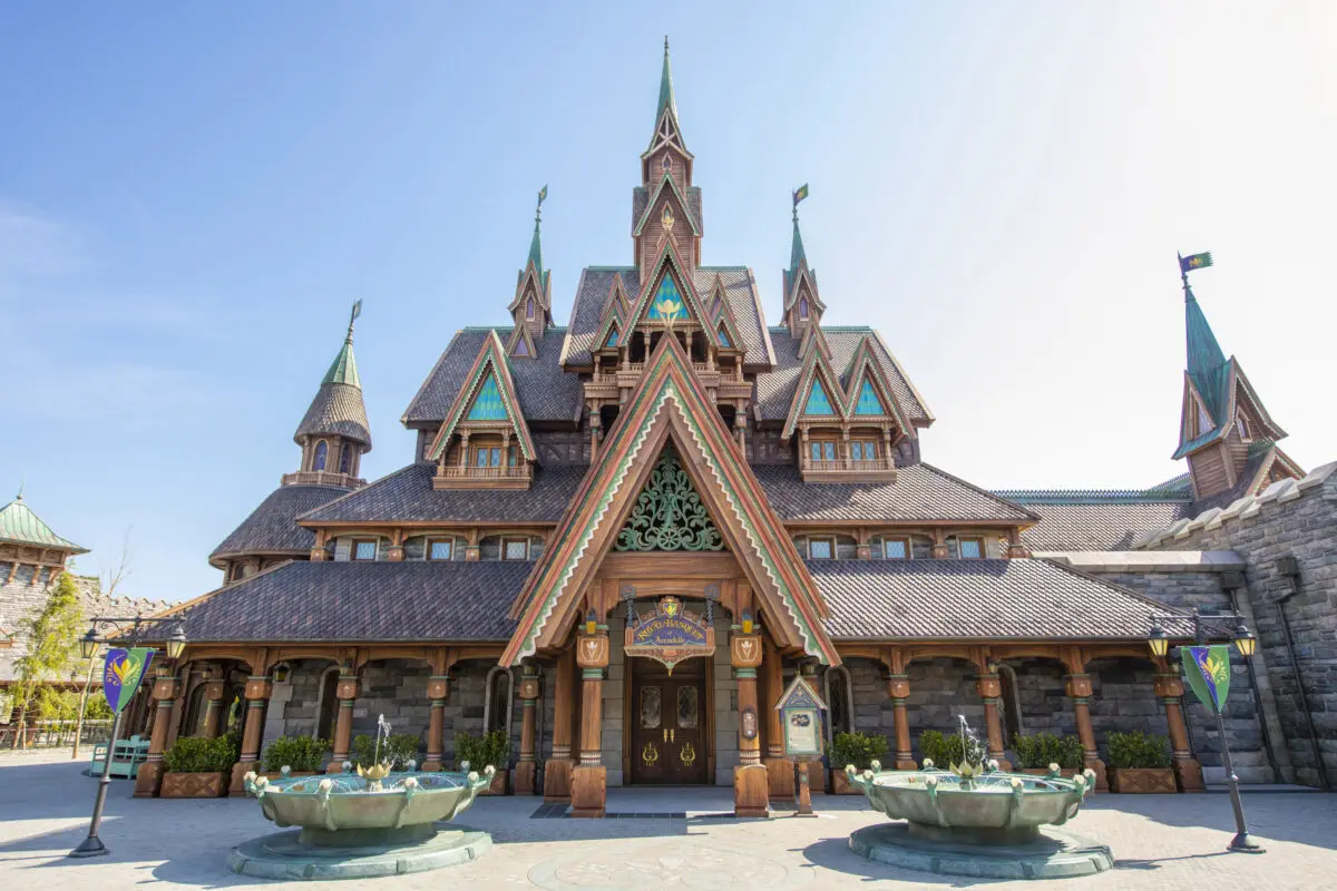 Front view of an ornate fairytale castle with intricate wooden carvings and multiple spires, under a clear blue sky.