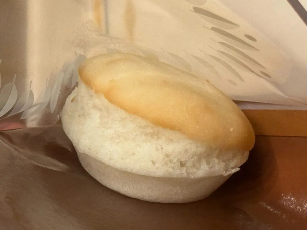 REVIEW: Every Meal from Tokyo Disney’s Most Expensive Counter Service Restaurant, Royal Banquet of Arendelle in Fantasy Springs 23 A close-up image of a vanilla muffin, partially wrapped in foil on a table surface. The muffin appears soft and freshly baked.