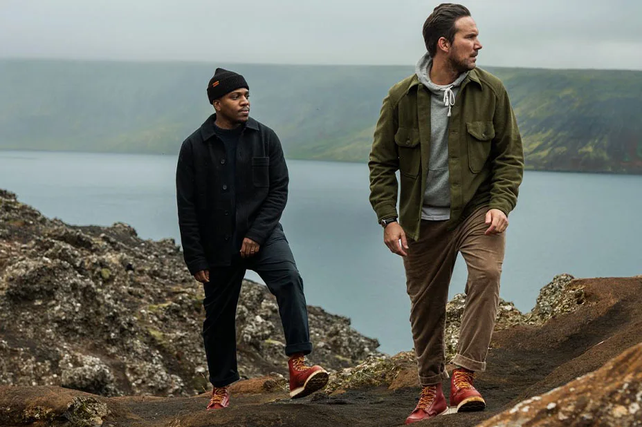 Two men standing on a rock by water