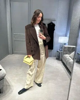 Alexa Chung wears a brown blazer with a yellow bag.