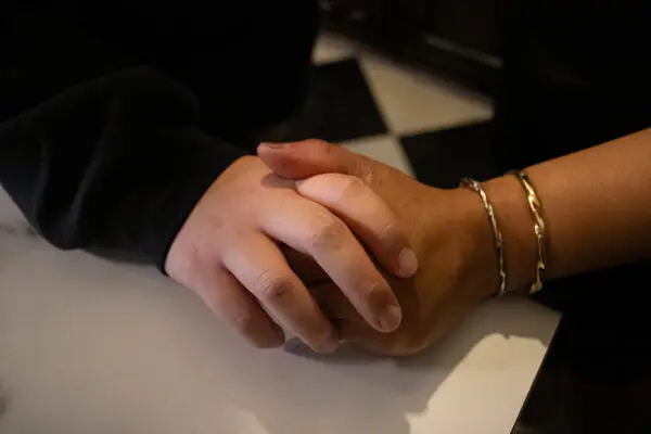 Two hands, one lighter skinned and one darker skinned, hold each other.