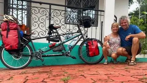 Tandem Travel Dave and Helen crouch for a photo by their bike 