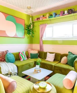 A green living room with a wall shelf of colorful books, a green couch, and a coffee table