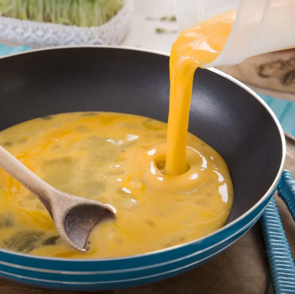 liquid egg for scrambled eggs is being poured into frying pan