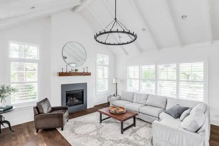 White raised ceilings in living room with mirror over fireplace, small wooden coffee table, and gray sectional couch