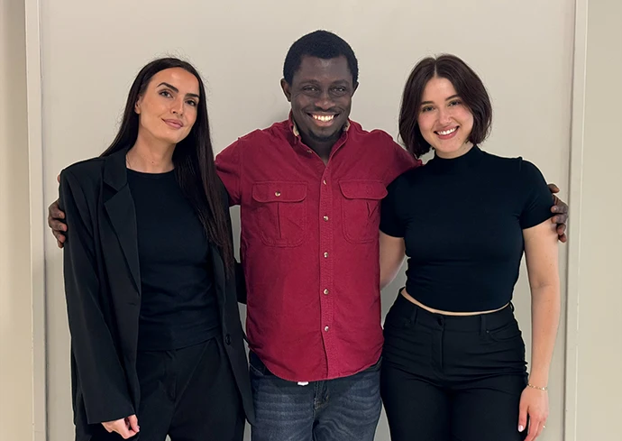 three people standing against a wall