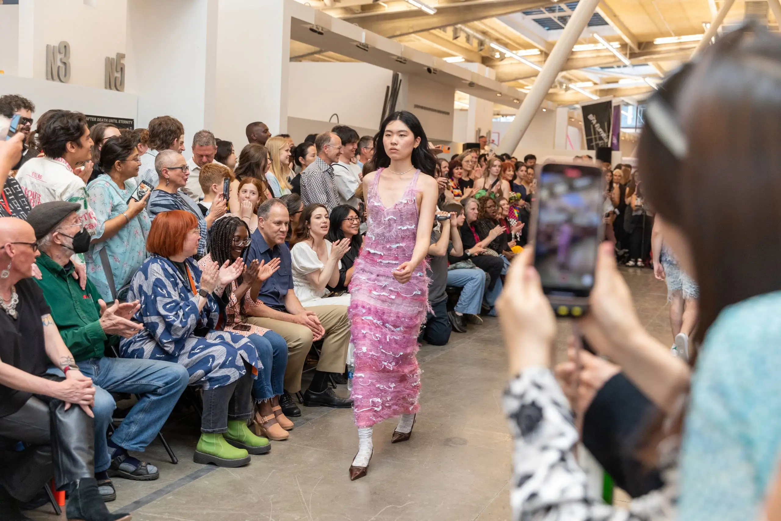 Woman in fuzzy pink dress surrounded by crowd