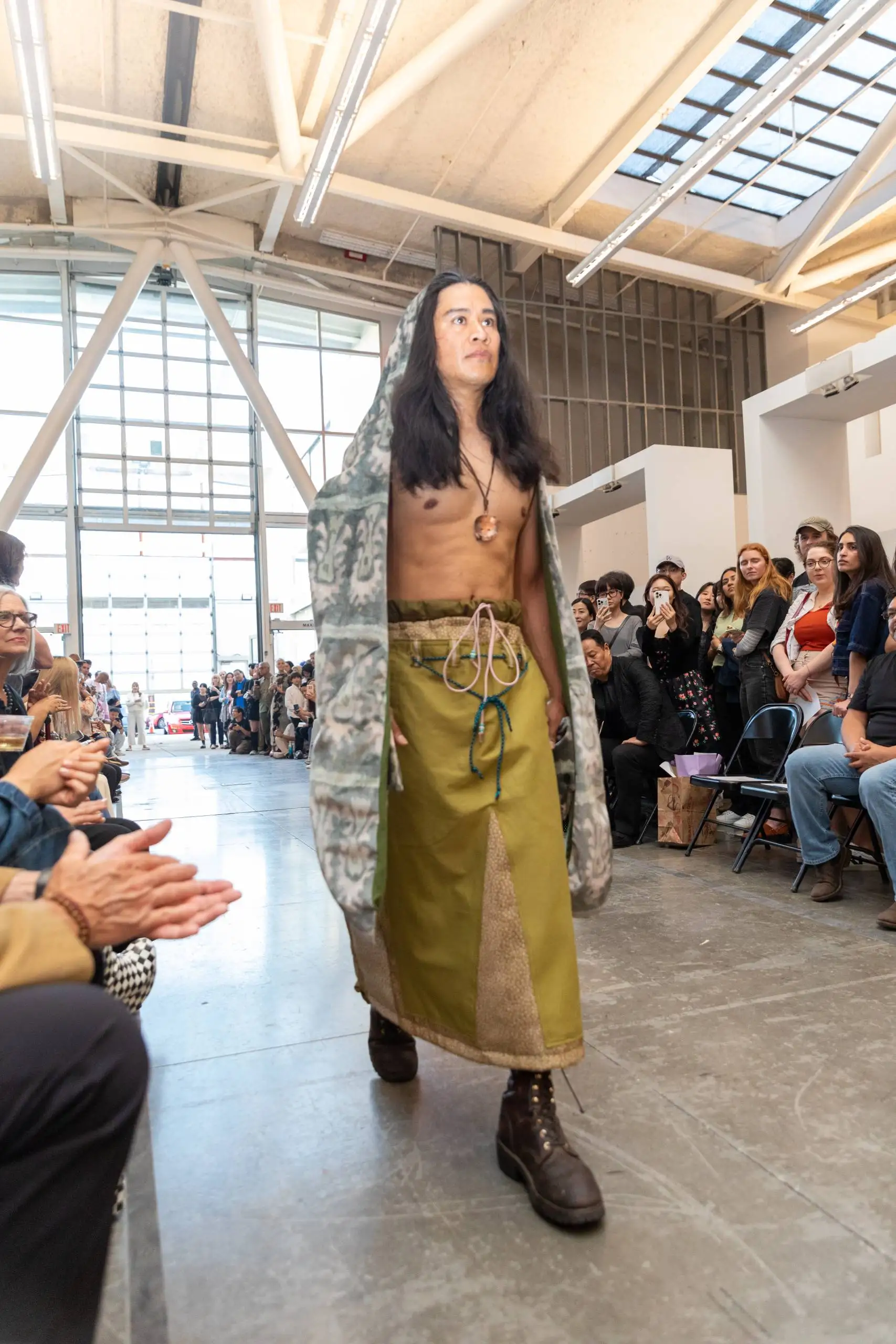 Model in draped head covering, layered skirts and boots