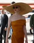 Young woman in oversized brimmed straw hat and a blood orange, strapless dress