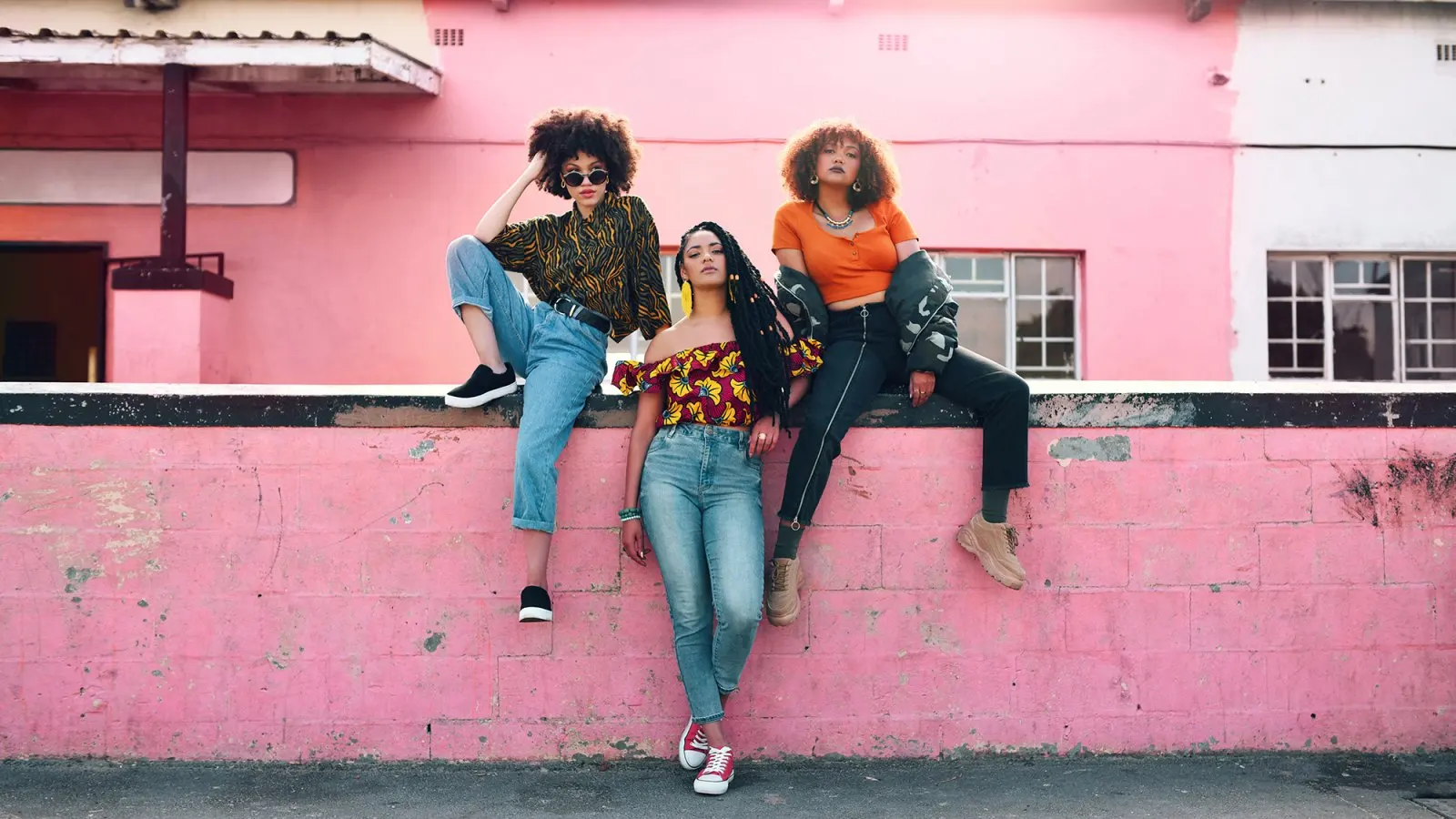 Full length shot of three attractive and stylish young women posing together against an urban background