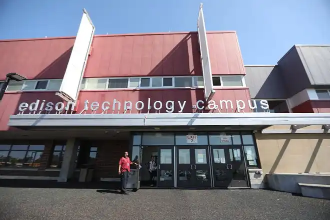 A security guard at Edison Career and Technology High School holds the door open for guests.