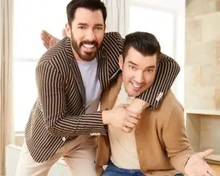 johnathan and drew scott hugging against a cream background