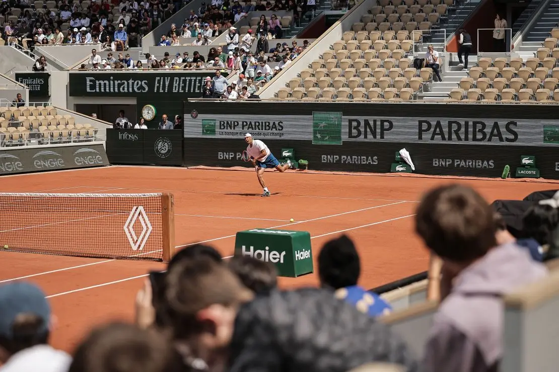 Rafael Nadal practices at Roland Garros in Paris with logos flanking the court.