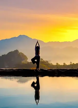 Woman practising stretching On the high mountain slopes in the morning mist and by the reflection ponds.