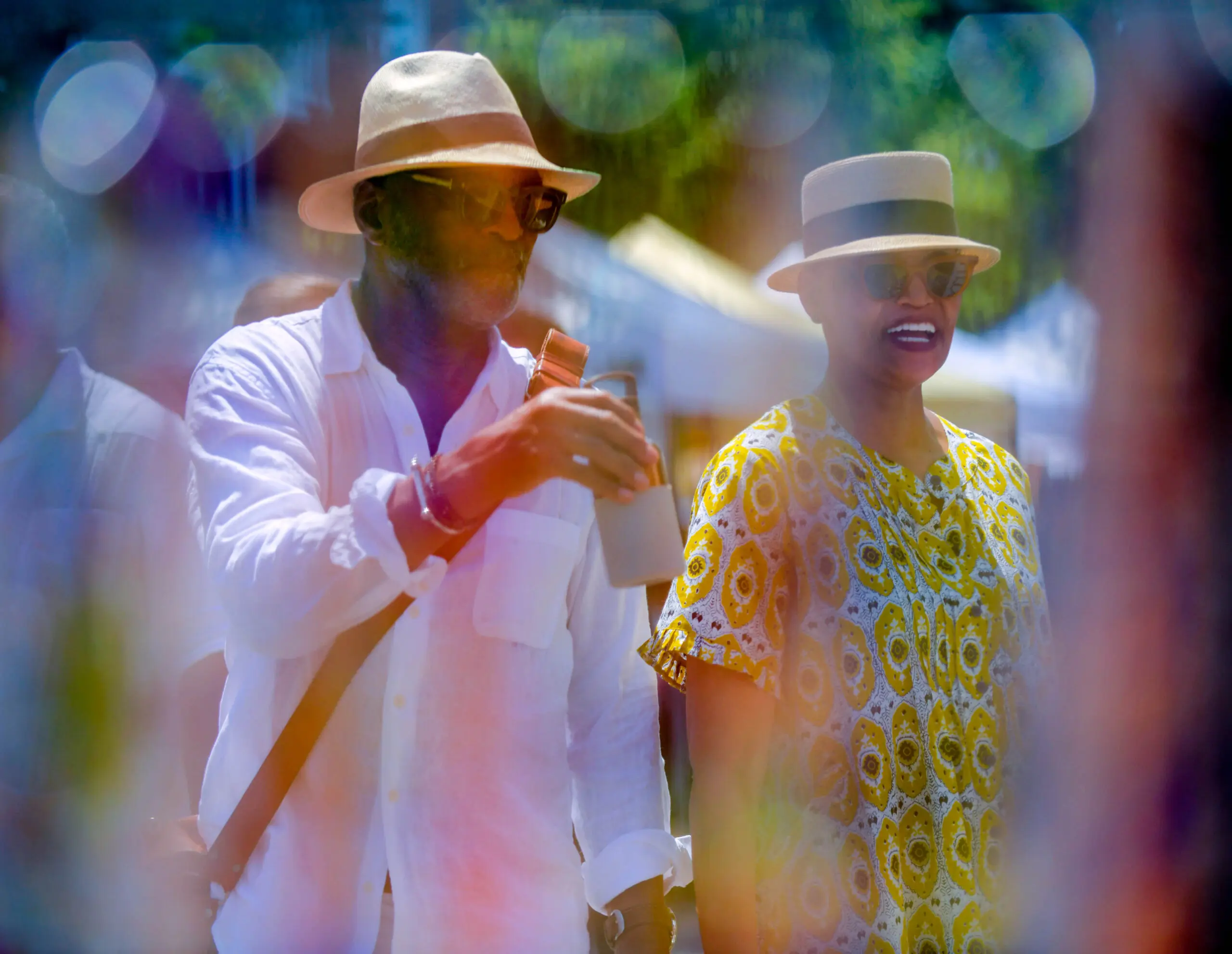 Seen through necklaces on display at glass Adorments, Thomas Clark and Teresa Clark of Washington, DC wave at people that they know during the annual Sowebo arts and music festival around Hollins Market. (Karl Merton Ferron/Staff)