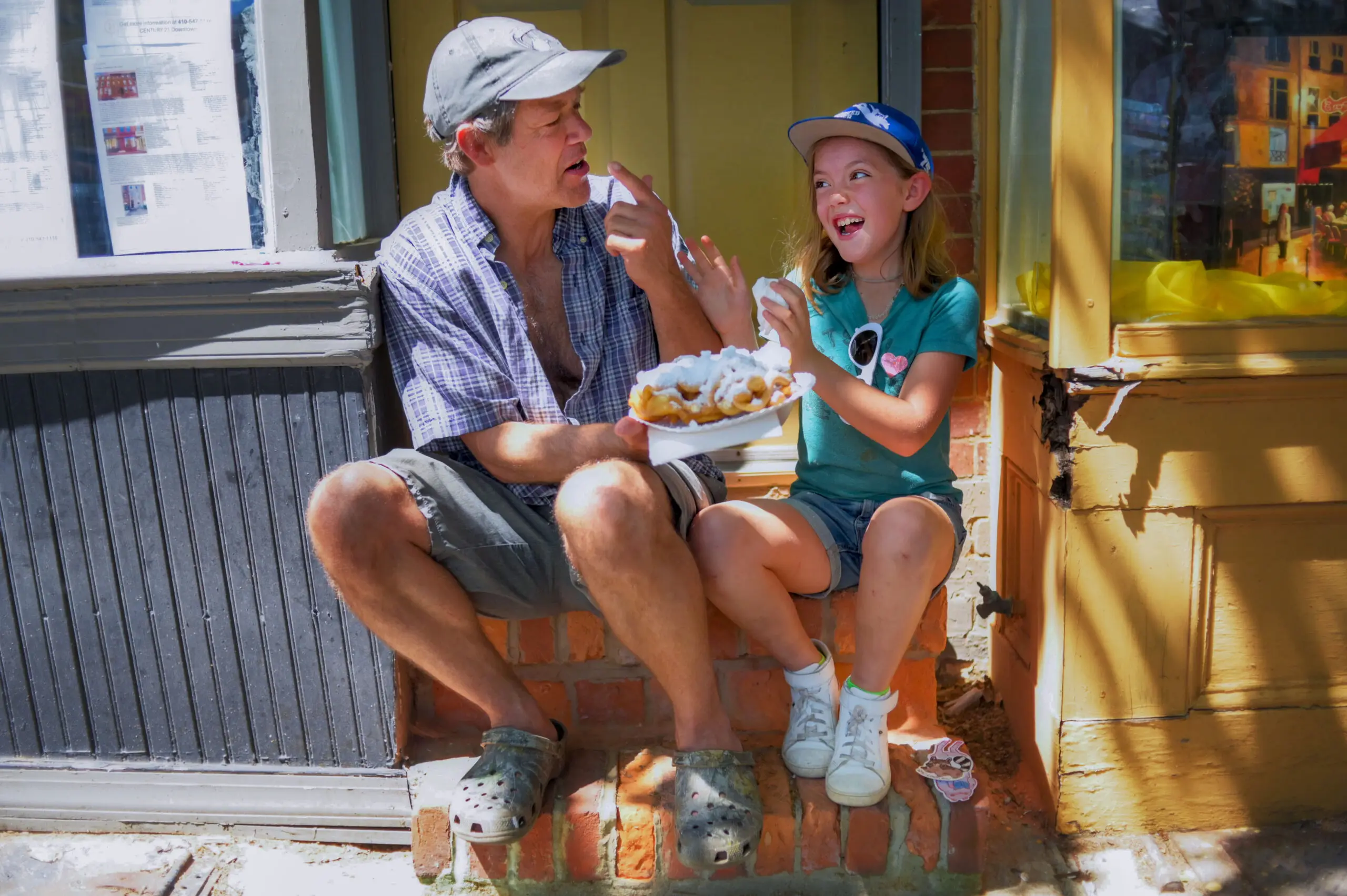 Jeff Jennings of Hampden shares funnel cake with niece Charley Demange, 9 during the annual Sowebo arts and music festival around Hollins Market. (Karl Merton Ferron/Staff)