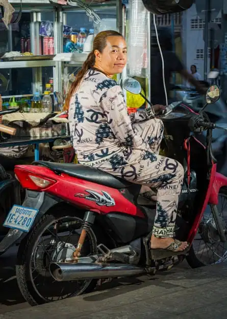 A woman wearing counterfeit Chanel sitting on scooter