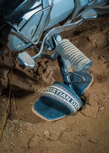 A 'Christian Dior' sandal under a motorcycle stand