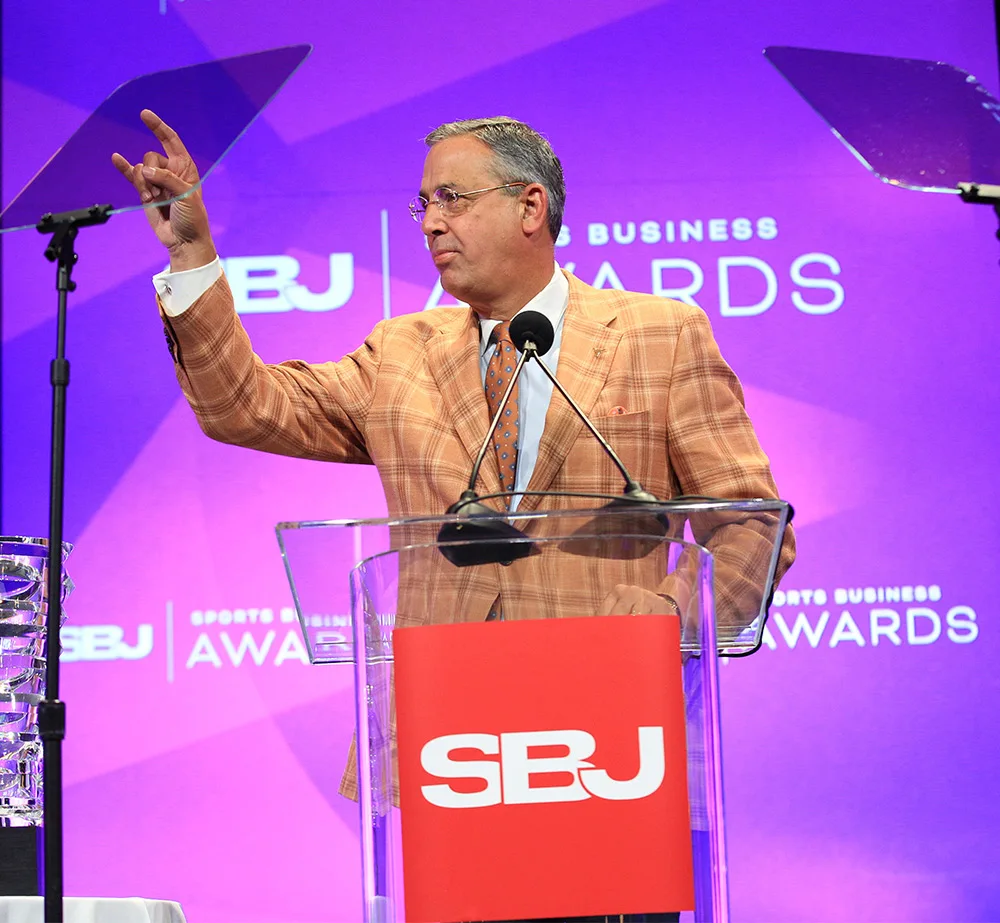 Chris Del Conte makes the University of Texas “hook ‘em” sign during his acceptance speech for Athletic Director of the Year.