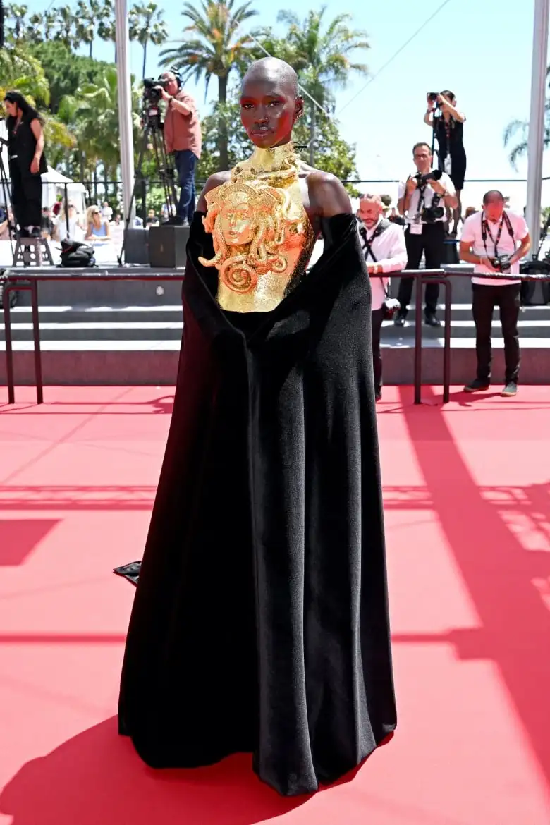 Mitchell Akat Maruko Raan on the red carpet wearing a black gown with a three-dimensional, gold Medusa breast plate.