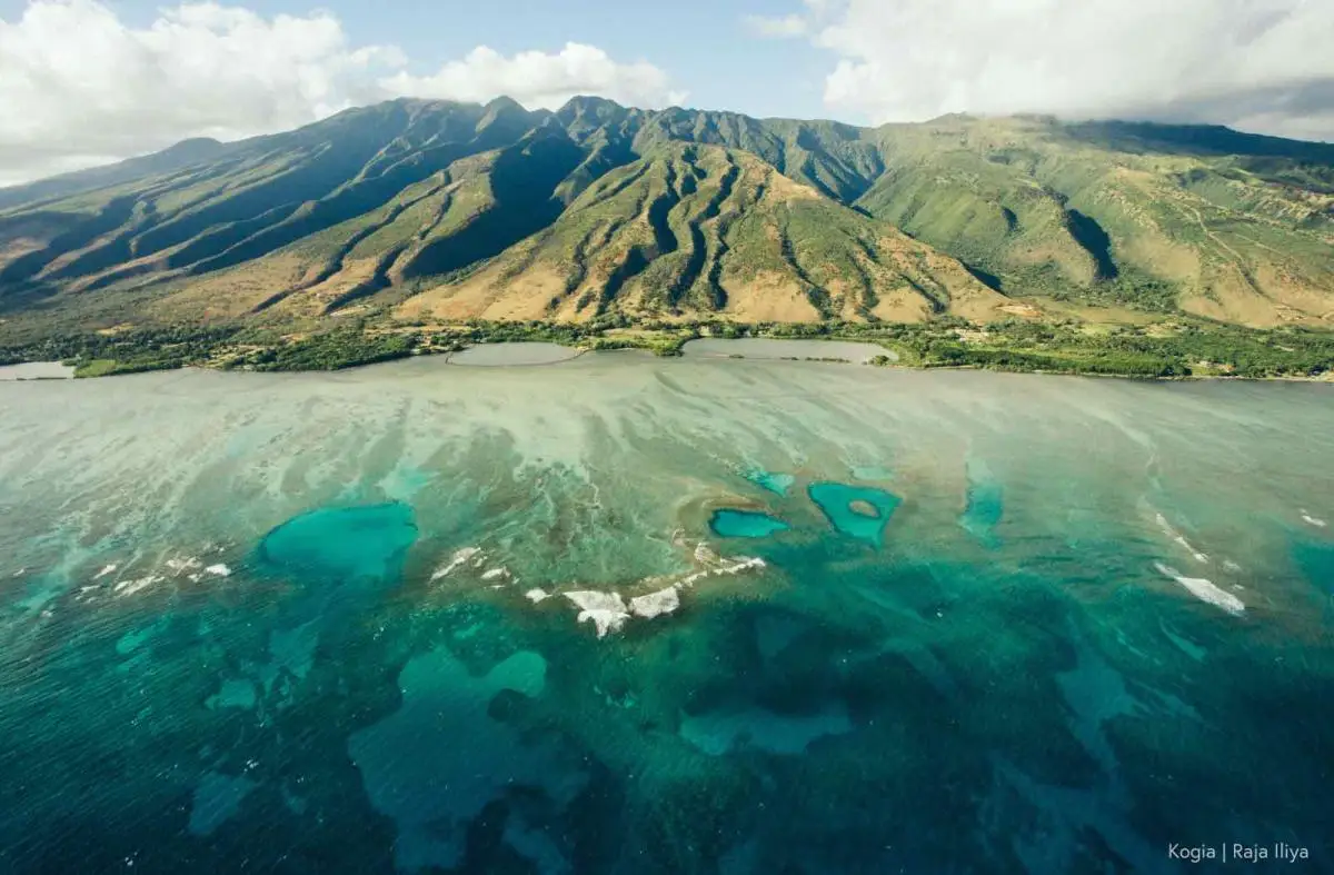 A view of aquamarine waters meeting the lush coast of a mountainous island