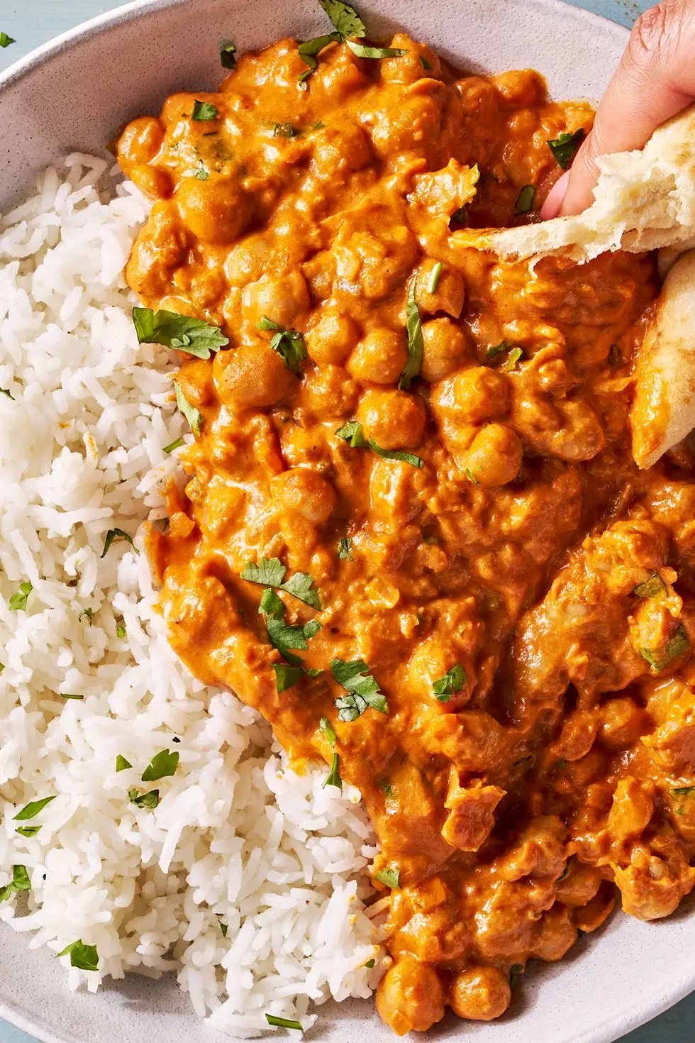 indian butter chickpeas and rice in a bowl with pita