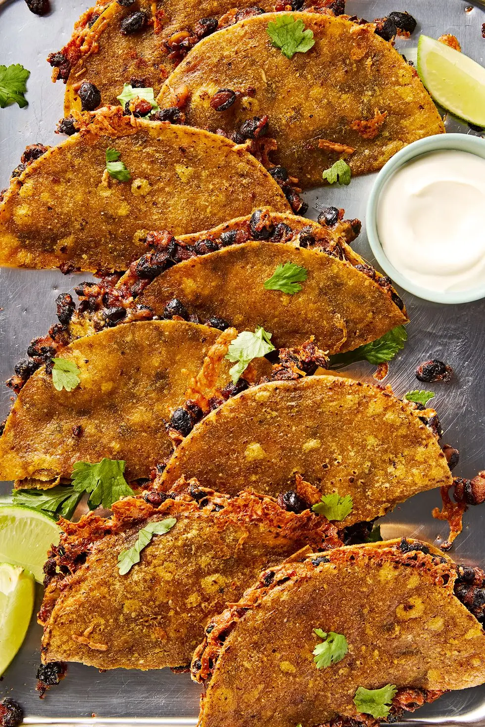 crispy sheet pan black bean tacos on a sheet pan with a bowl of sour cream