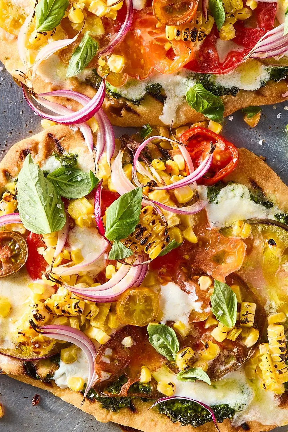 flatbread topped with pesto, corn, sliced onions, cheese, and tomatoes