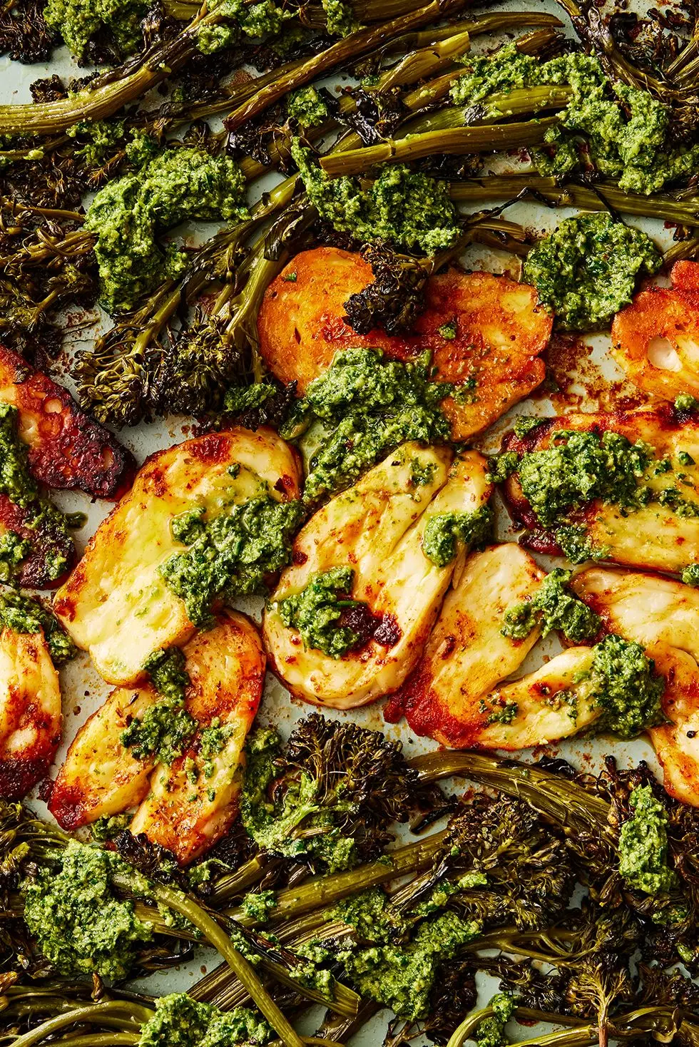 roasted halloumi and broccolini with a pesto sauce on a sheet pan