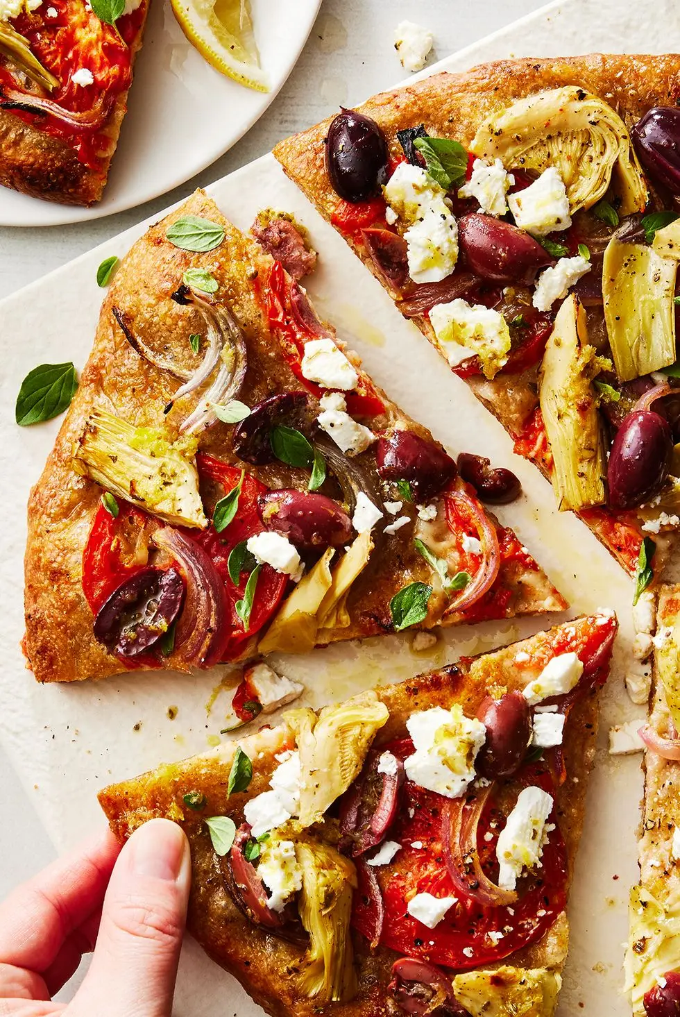 skillet pizza topped with olives, artichokes, tomatoes, feta, and onions