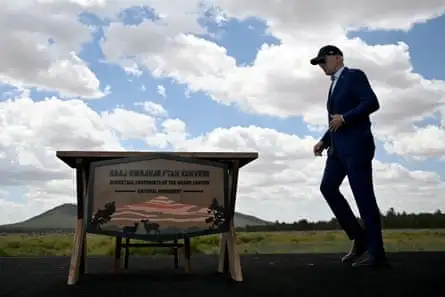 a man in a suit and baseball cap walks in a grassy area