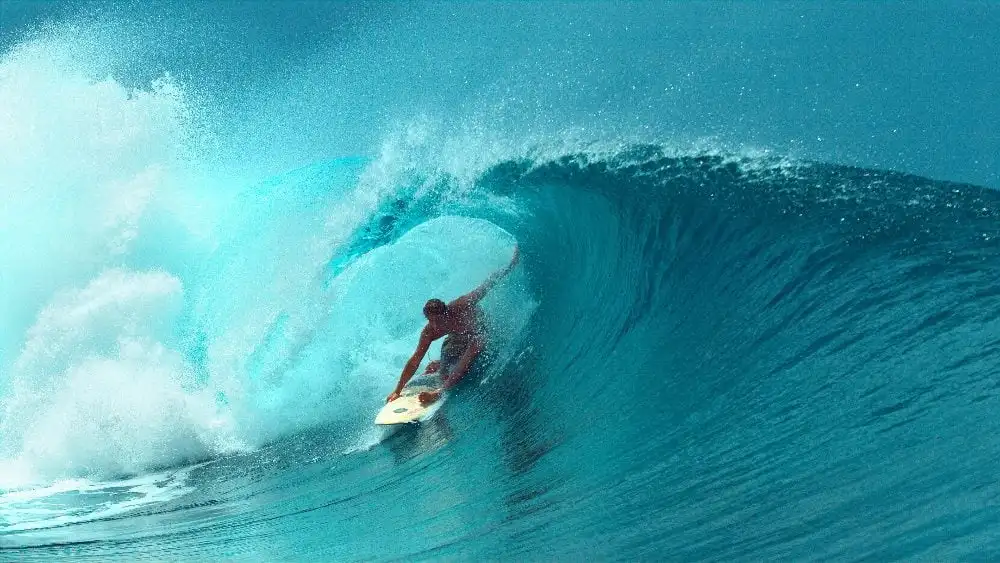 A surfer is riding a powerful, curling wave. The ocean's vibrant blue and turquoise colors highlight the dynamic movement of the water. The surfer, poised and focused, navigates the wave expertly, emphasizing both the challenge and exhilaration of the activity. The scene captures the essence of surfing with a clear sky in the background and the sun reflecting off the water in piece about UX design.