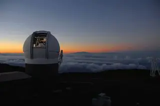 A photo of the pan-starrs telescope with clouds around it