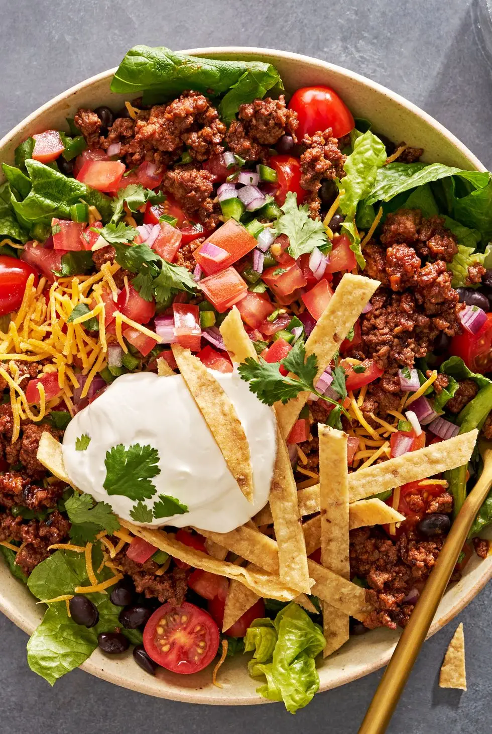 taco salad with sour cream, tomatoes, ground beef, and tortilla strips