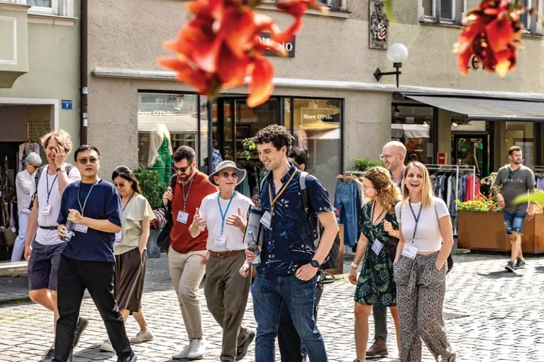 Young Scientist attendees of the 72nd Lindau Nobel Laureate Meeting walk through streets of Lindau while talking with Nobel Prize winner Randy Schekman