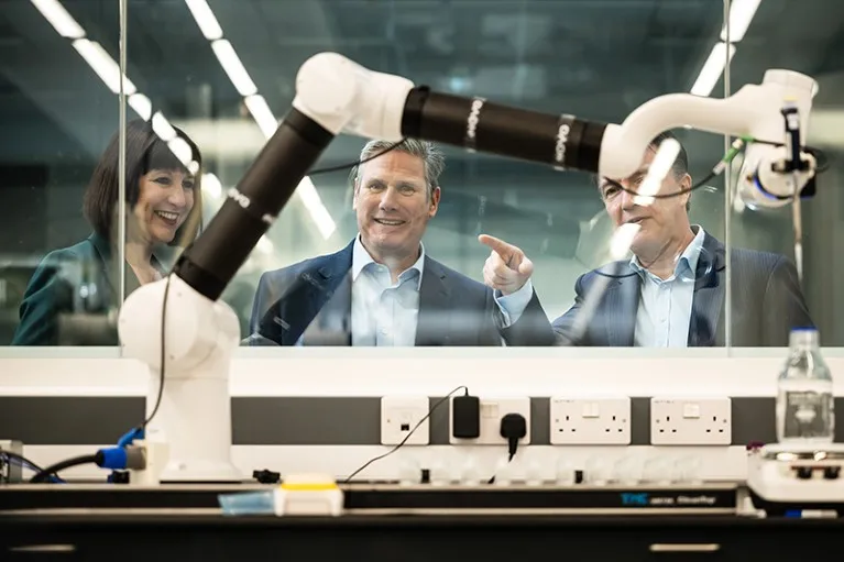 Leader of the Labour Party Keir Starmer and Shadow Chancellor Rachel Reeves view robotic equipment through a window during a visit to the Materials Innovation Factory in Liverpool, England