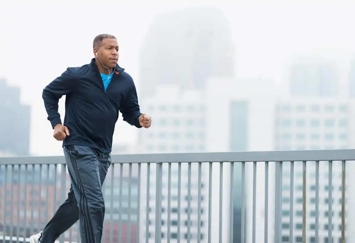 african american man running outside with cityscape background