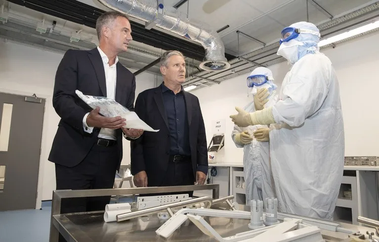 Sir Keir Starmer and Peter Kyle (left) talk to two AstraZeneca employees in protective attire as they visit an AstraZeneca laboratory in Macclefield in 2023.