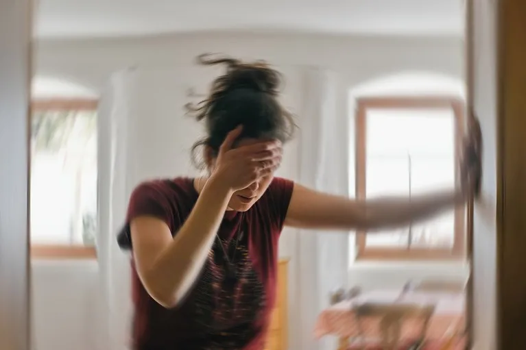 Blurred photo of a woman clutching her head whilst suffering from a migraine.