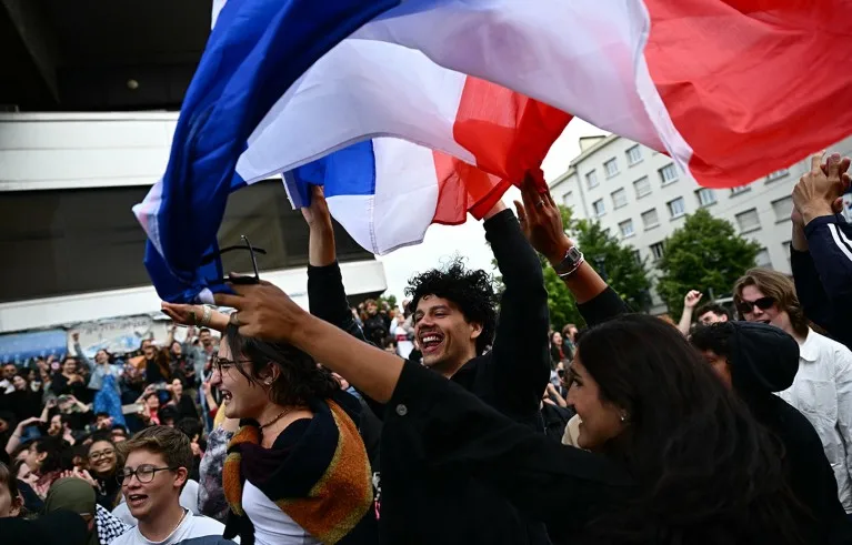 People celebrate with a French national flag during a rally in Nantes, western France.