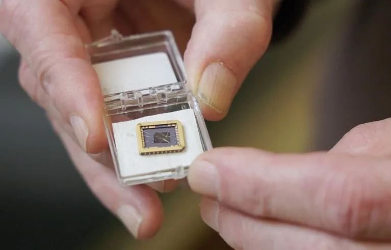 Close of a researchers hands holding a graphene device grown on a silicon carbide substrate chip.