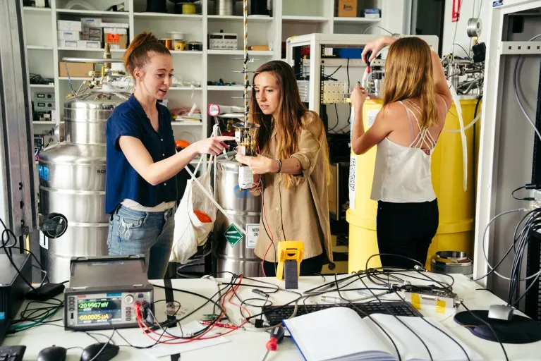 Irene Fernández de Fuentes and two female colleagues work on parts of a quantum computer in a laboratory