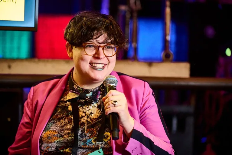 Tzula Propp holding a microphone on stage during a panel discussion on diversity in quantum science