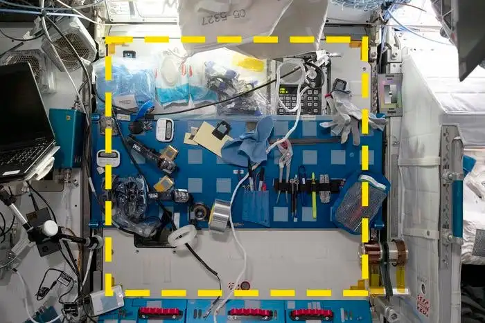 A sample location from the Sampling Quadrangle Assemblages Research Experiment (SQuARE), Square 03 in the starboard Maintenance Work Area of the International Space Station. An open crew berth is visible at right. The yellow dotted line indicates the boundaries of the sample area.